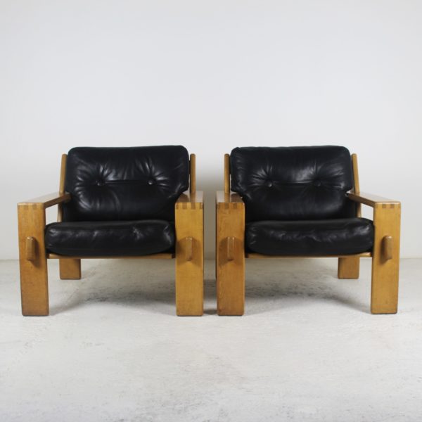 Paire de fauteuils scandinaves vintage 1960, en chêne et coussins en cuir noir.