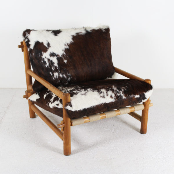 Fauteuil vintage des années 60, en bois de mélèze et coussins en peau de vache.