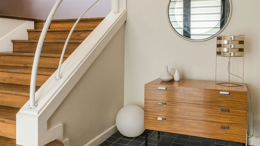 Décoration d'une maison, décor vintage avec une commode années 50 d'André Monpoix et miroir rond en verre années 70.
